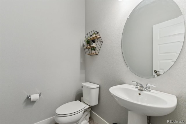 half bath with a sink, baseboards, and toilet