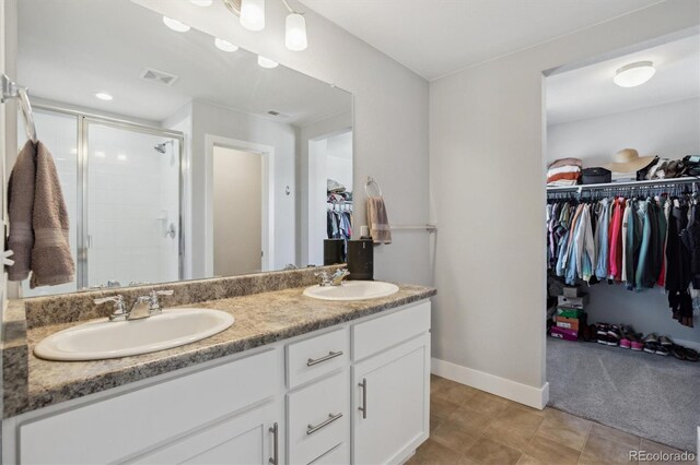 full bathroom with a spacious closet, visible vents, a shower stall, and a sink