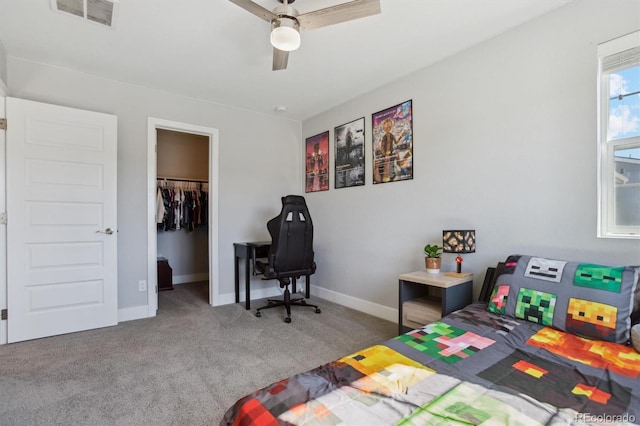 carpeted bedroom featuring visible vents, a walk in closet, a closet, baseboards, and ceiling fan