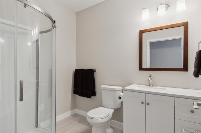 full bathroom featuring vanity, wood finished floors, baseboards, a shower stall, and toilet