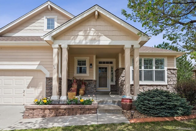 1844 S Jay Way, Lakewood, CO 80232 - view of exterior entry featuring a porch, roof with shingles, stone siding, concrete driveway, and a garage
