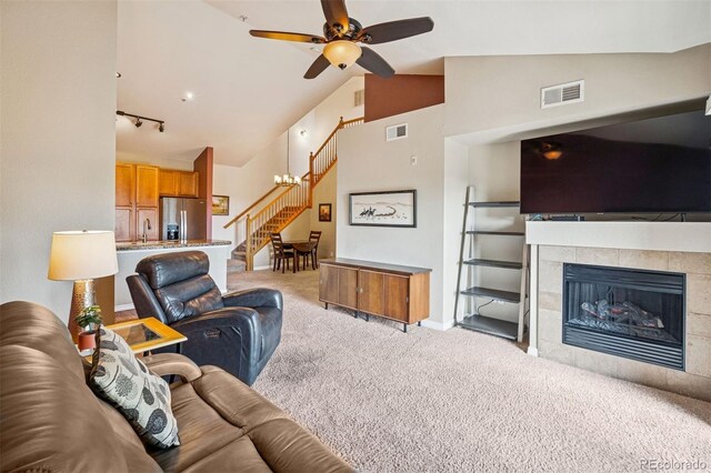 8778 S Kipling Way Unit 304, Littleton, CO 80127 - carpeted living room with stairs, a ceiling fan, a fireplace, high vaulted ceiling, and a sink