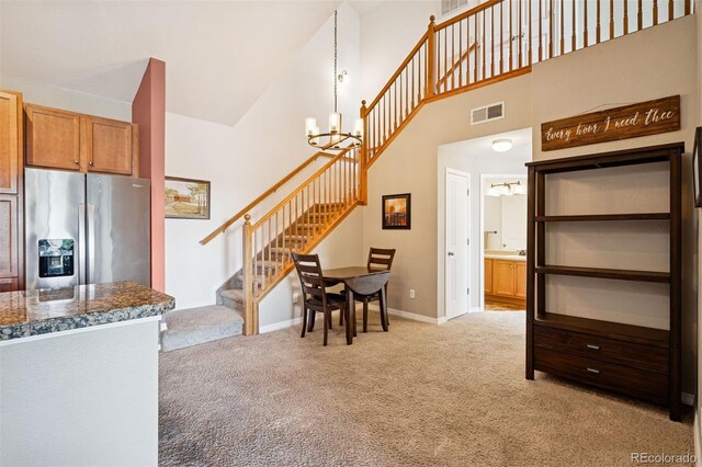 8778 S Kipling Way Unit 304, Littleton, CO 80127 - dining area with high vaulted ceiling, a chandelier, light carpet, stairs, and baseboards