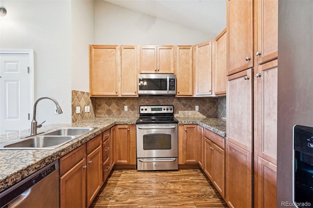 8778 S Kipling Way Unit 304, Littleton, CO 80127 - kitchen featuring appliances with stainless steel finishes, a sink, vaulted ceiling, light wood-type flooring, and backsplash