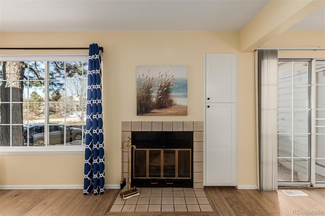 unfurnished living room with wood-type flooring and a tile fireplace