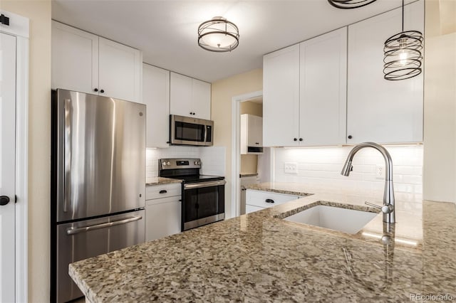 kitchen with white cabinetry, backsplash, stainless steel appliances, and light stone countertops