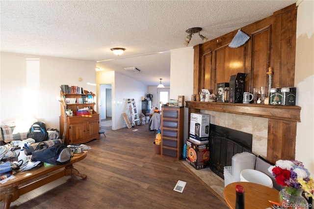 living room with a tiled fireplace, a textured ceiling, and hardwood / wood-style flooring