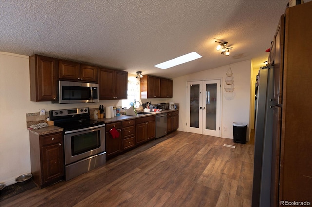 kitchen with dark hardwood / wood-style flooring, stainless steel appliances, a textured ceiling, vaulted ceiling with skylight, and sink