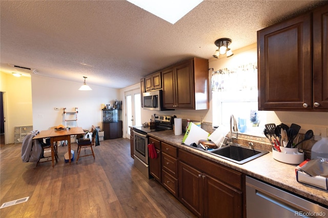 kitchen with sink, a textured ceiling, decorative light fixtures, stainless steel appliances, and dark hardwood / wood-style floors