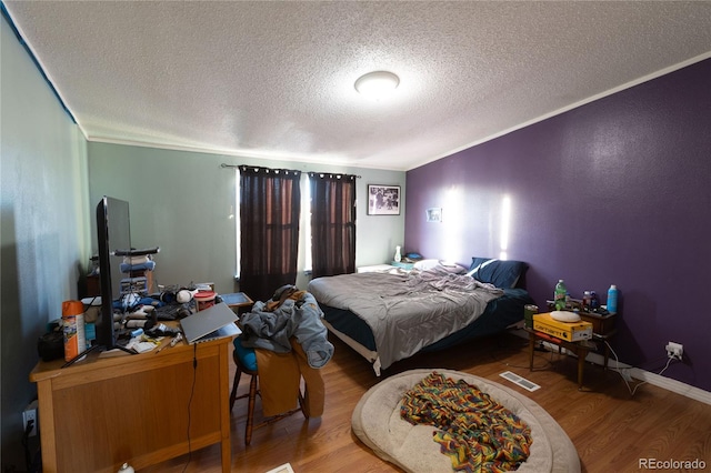 bedroom with hardwood / wood-style flooring, ornamental molding, and a textured ceiling