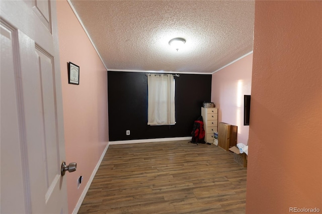 empty room featuring wood-type flooring, a textured ceiling, and crown molding