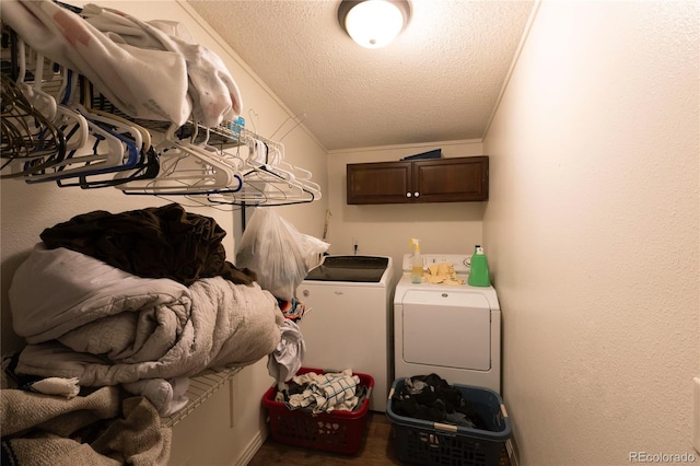 laundry room with cabinets, ornamental molding, a textured ceiling, and washer and clothes dryer