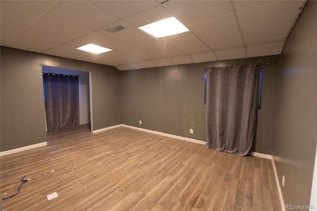 empty room with a drop ceiling and hardwood / wood-style flooring