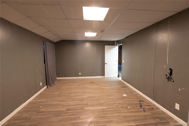 spare room featuring wood-type flooring and a drop ceiling