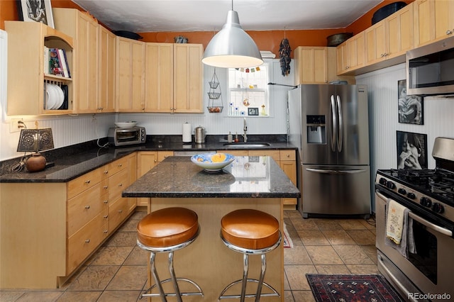 kitchen featuring appliances with stainless steel finishes, a center island, light brown cabinetry, and sink