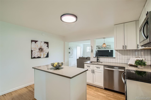 5563 Newland Way, Arvada, CO 80002 - kitchen with stainless steel appliances, white cabinets, tasteful backsplash, light wood finished floors, and light countertops