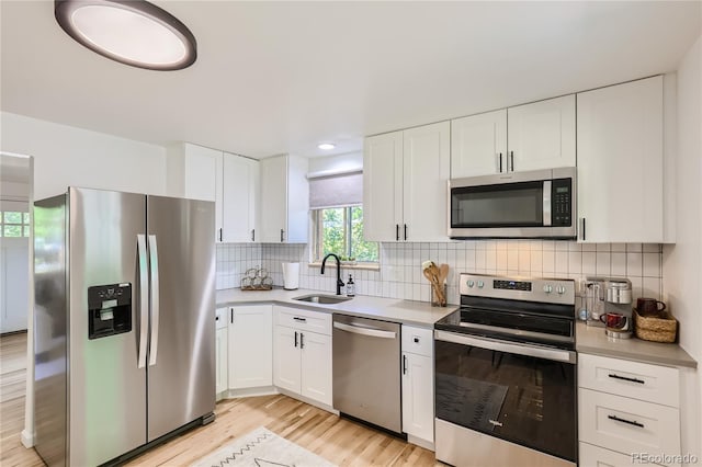 5563 Newland Way, Arvada, CO 80002 - kitchen with stainless steel appliances, white cabinets, light wood-type flooring, light countertops, and backsplash