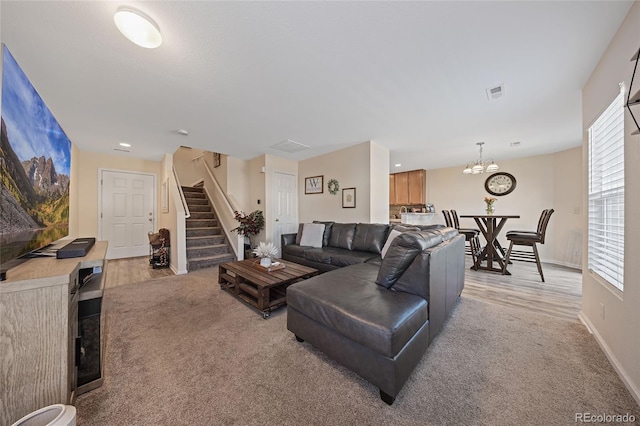 carpeted living room featuring an inviting chandelier