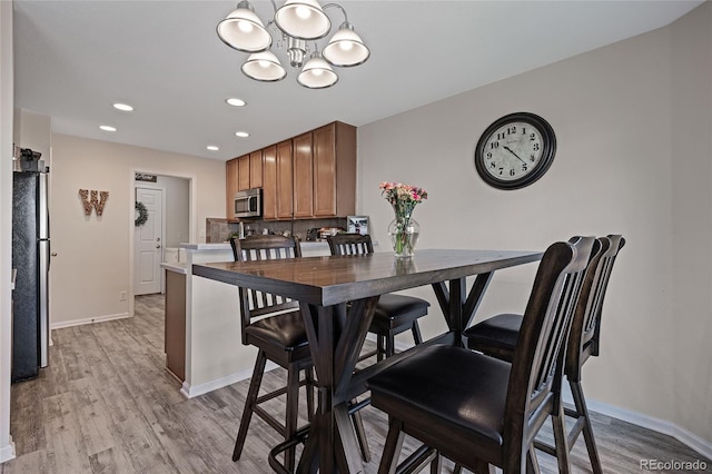 dining area with a notable chandelier and light hardwood / wood-style flooring