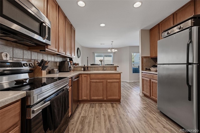 kitchen with stainless steel appliances, tasteful backsplash, a chandelier, decorative light fixtures, and light wood-type flooring