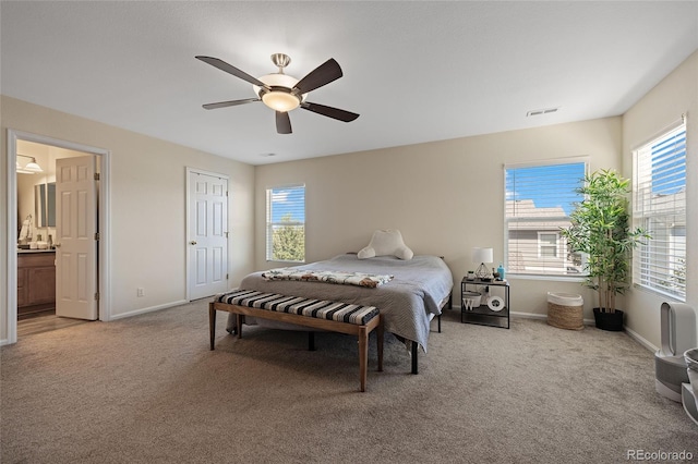 carpeted bedroom with multiple windows, connected bathroom, and ceiling fan