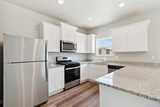 kitchen featuring appliances with stainless steel finishes, a sink, white cabinets, and recessed lighting