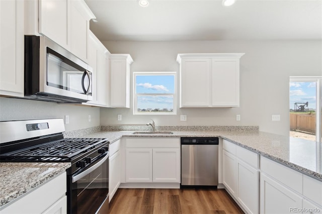 kitchen with appliances with stainless steel finishes, a sink, white cabinets, dark wood-style flooring, and recessed lighting