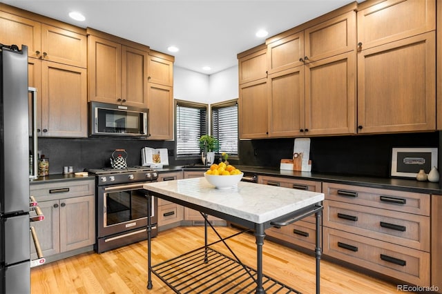 600 Cascade Dr, Golden, CO 80403 - kitchen featuring stainless steel appliances, decorative backsplash, light wood-type flooring, dark countertops, and recessed lighting