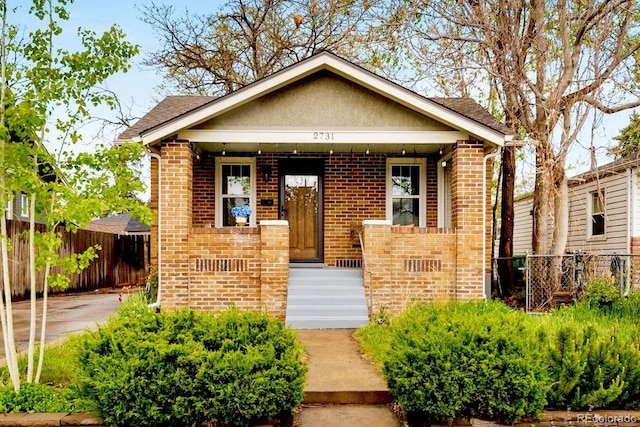 view of front of home featuring brick siding, fence, and a shingled roof