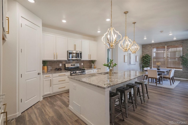 kitchen with white cabinets, a kitchen island with sink, dark wood-type flooring, and stainless steel appliances