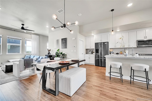 1575 W 68th Ave, Denver, CO 80221 - kitchen with stainless steel appliances, a breakfast bar area, white cabinetry, ceiling fan, and decorative backsplash