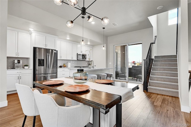 1575 W 68th Ave, Denver, CO 80221 - dining space with light wood finished floors, stairway, and a chandelier