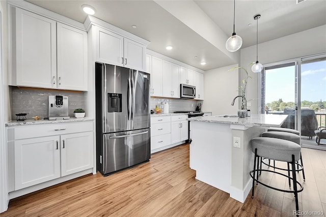 1575 W 68th Ave, Denver, CO 80221 - kitchen with stainless steel appliances, light wood-type flooring, white cabinetry, tasteful backsplash, and a breakfast bar area