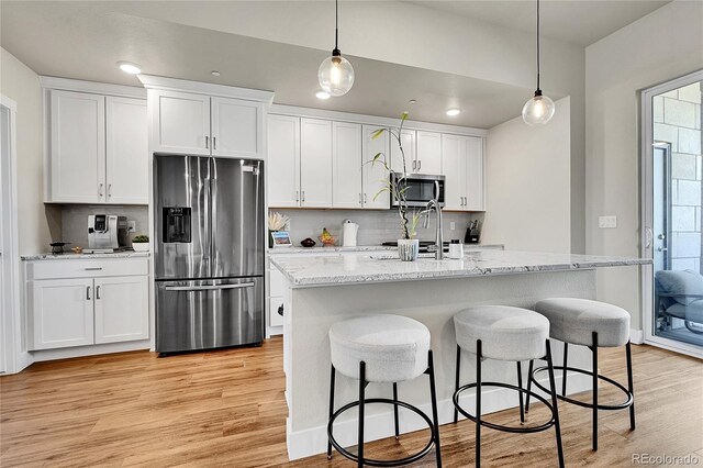 1575 W 68th Ave, Denver, CO 80221 - kitchen featuring appliances with stainless steel finishes, light wood-style flooring, white cabinets, a breakfast bar, and recessed lighting