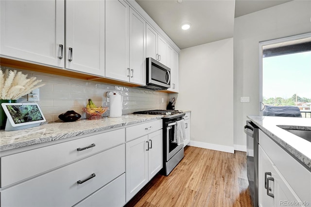 1575 W 68th Ave, Denver, CO 80221 - kitchen with stainless steel appliances, light wood-style flooring, white cabinets, backsplash, and light stone counters