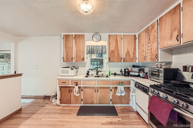 kitchen with backsplash, dishwasher, light wood-type flooring, gas stove, and sink