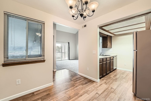 kitchen featuring hanging light fixtures, sink, light hardwood / wood-style flooring, appliances with stainless steel finishes, and dark brown cabinetry