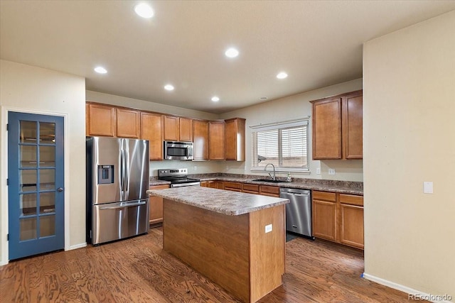 kitchen featuring recessed lighting, a sink, appliances with stainless steel finishes, a center island, and dark wood-style floors