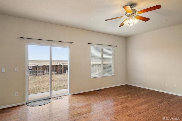 unfurnished room with visible vents, plenty of natural light, baseboards, and wood finished floors