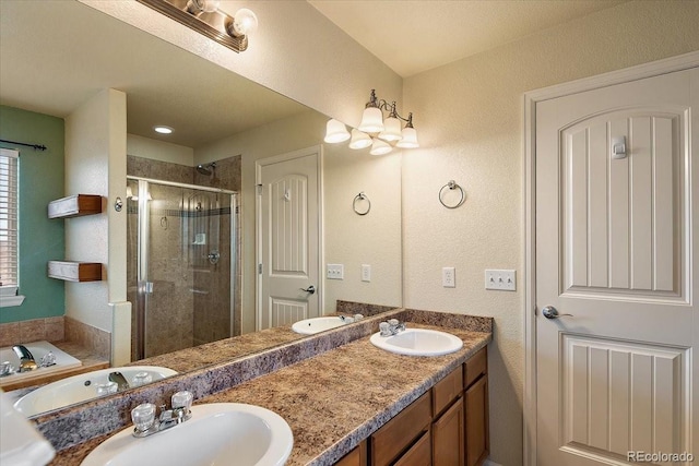 full bathroom with double vanity, a stall shower, and a sink