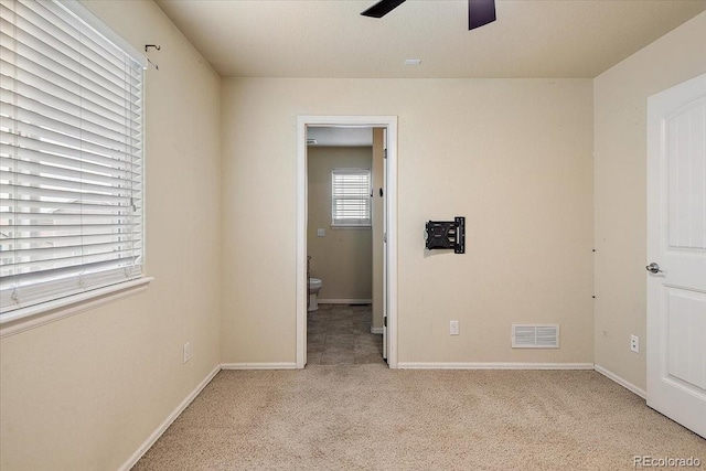 unfurnished room featuring a ceiling fan, visible vents, light carpet, and baseboards