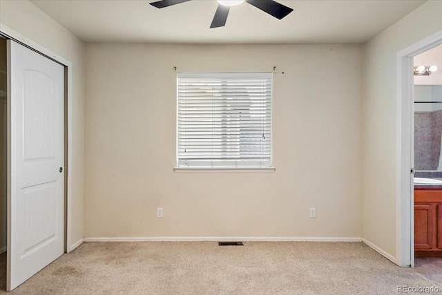 unfurnished bedroom with baseboards, visible vents, a ceiling fan, connected bathroom, and light colored carpet