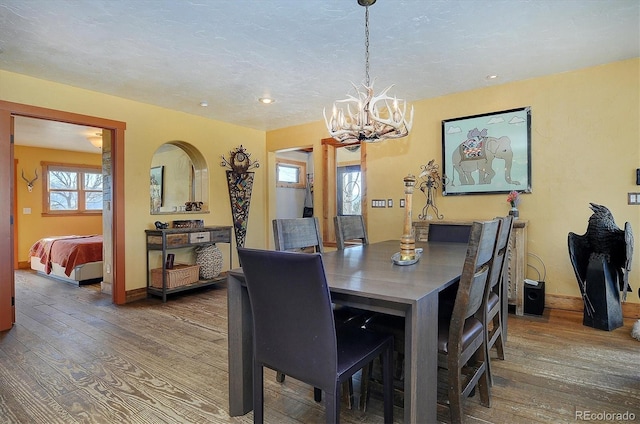 dining room featuring dark hardwood / wood-style floors, a wealth of natural light, a textured ceiling, and an inviting chandelier