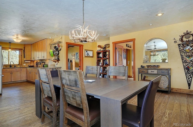 dining room featuring sink, dark wood-type flooring, a chandelier, and a textured ceiling