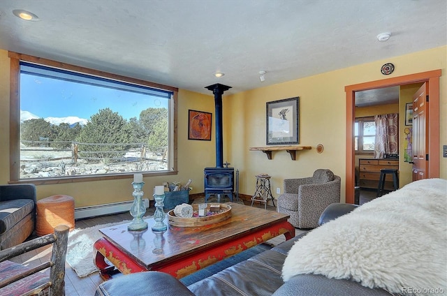 bedroom with baseboard heating, hardwood / wood-style floors, and a wood stove