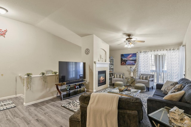 living area with baseboards, ceiling fan, wood finished floors, and a fireplace