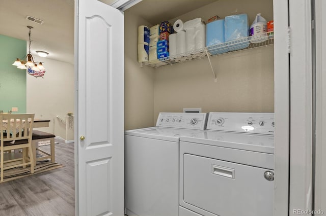 washroom with laundry area, wood finished floors, visible vents, and washing machine and clothes dryer