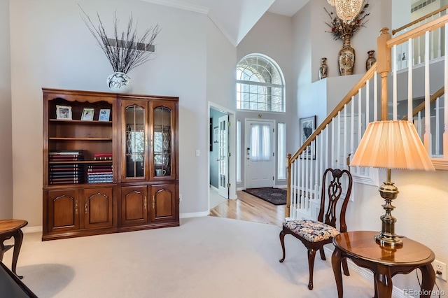 foyer entrance with a notable chandelier, baseboards, stairway, a high ceiling, and light colored carpet