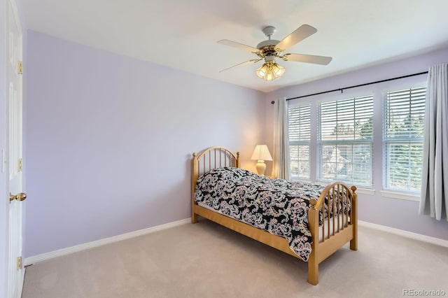carpeted bedroom featuring multiple windows, baseboards, and ceiling fan