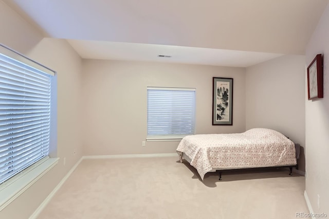 bedroom featuring visible vents, baseboards, multiple windows, and light colored carpet